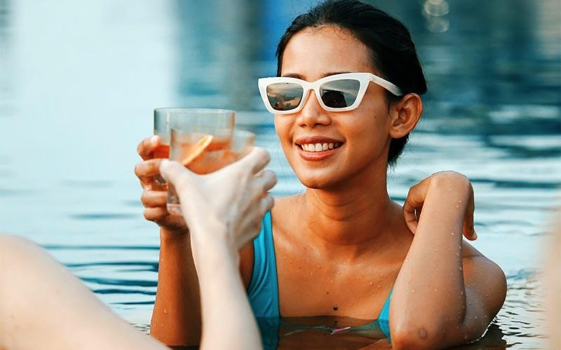 Women clinking drinking glass with friend in resort-style pool at The Hudson, an apartment complex in Chattanooga, TN